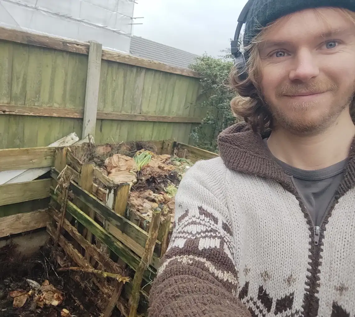 The gardener smiling beside a compost bay he has built in a Wirral garden